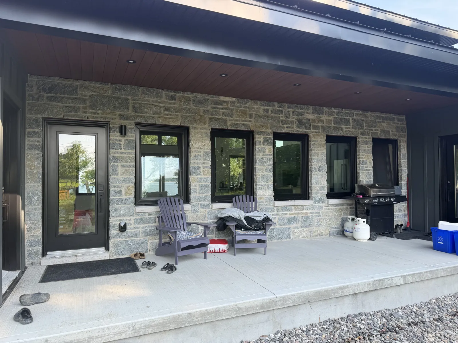Waterfront home with stone facade and covered porch
